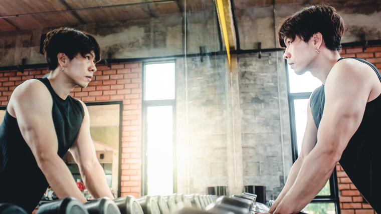 A person stares themself down in the gym mirror.