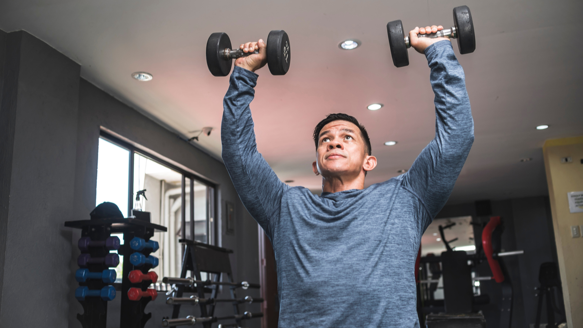 A person presses dumbbells overhead.