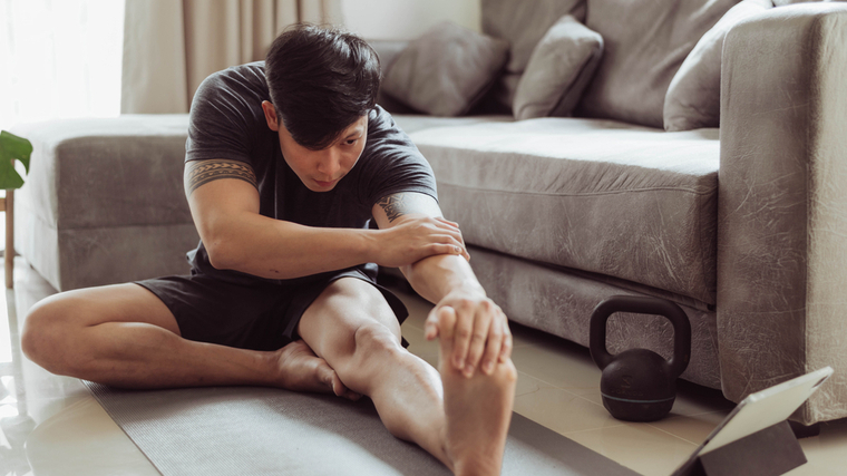 A person stretches on a yoga mat at home.