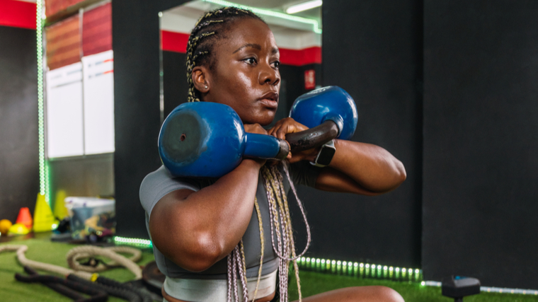 A person performs a double kettlebell squat.