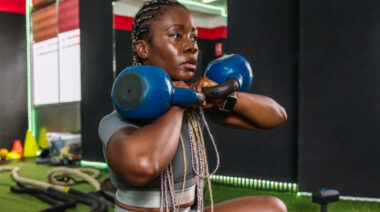 A person performs a double kettlebell squat.