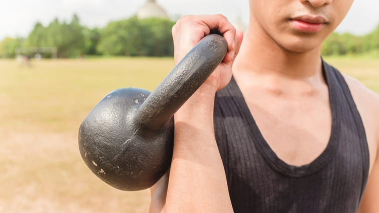 A person racks a kettlebell outdoors.