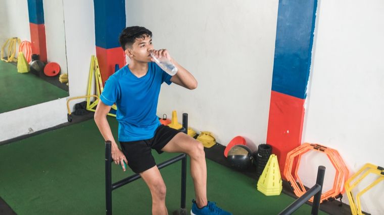 A person rests and drinks water after a workout.