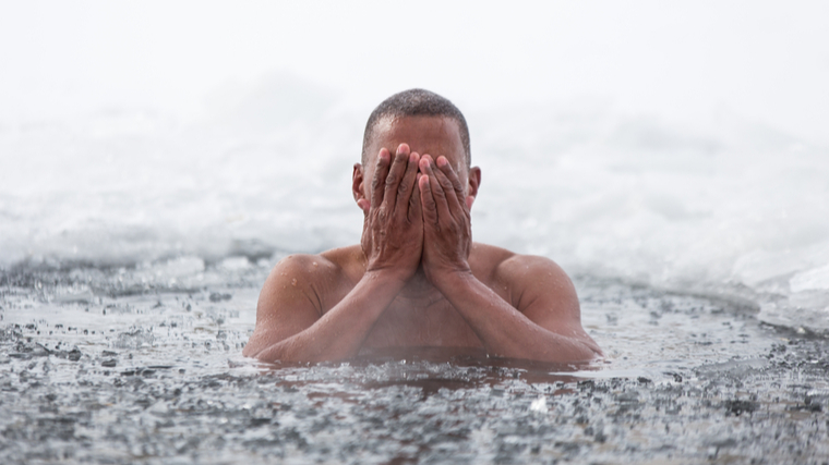 A person emerges from icy water.