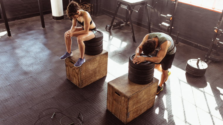 Two gym partners rest after performing box jumps.