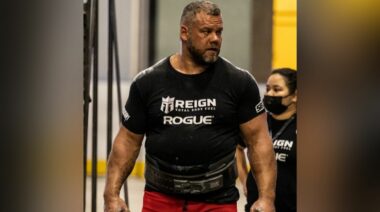 Strongman Rauno Heinla walking toward camera wearing a black t-shirt and lifting belt