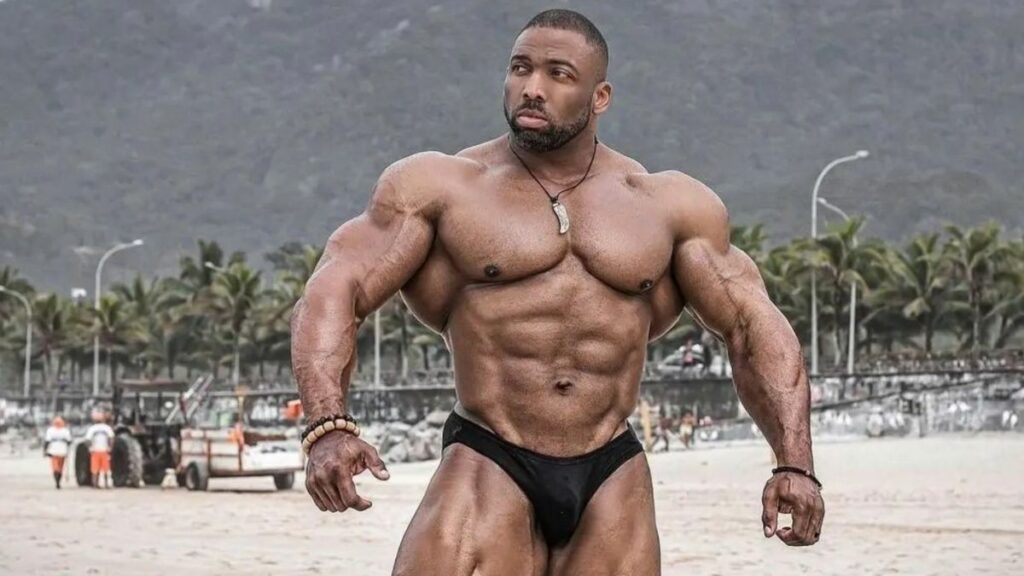 Bodybuilder Cedric McMillan posing on a beach