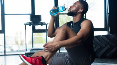 A person sits in the gym and drinks water.
