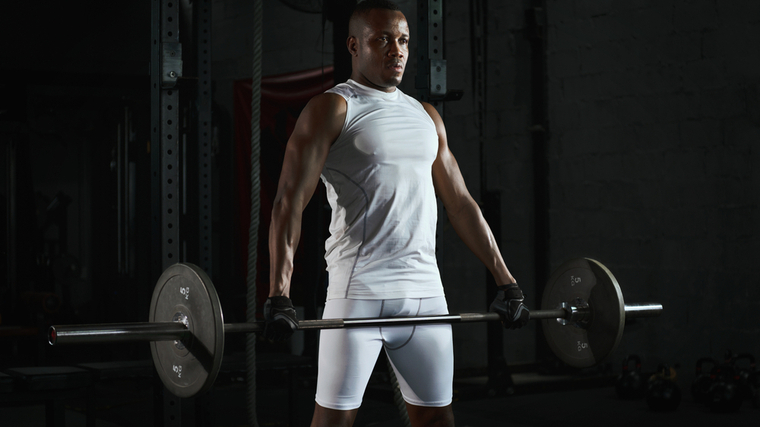 A person performs a barbell shrug.