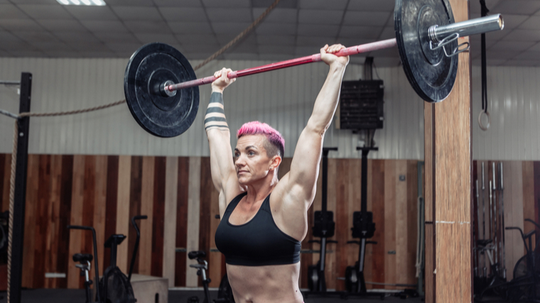 A person holds a barbell overhead.