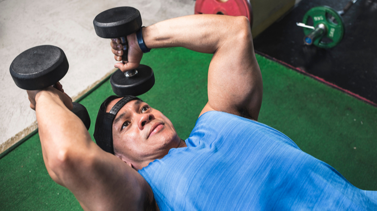 A person performs a dumbbell skull crusher.