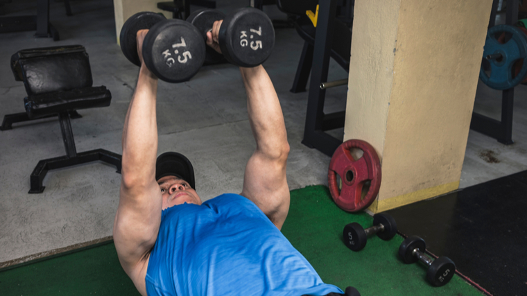 A person presses two dumbbells overhead on a bench with a neutral grip.