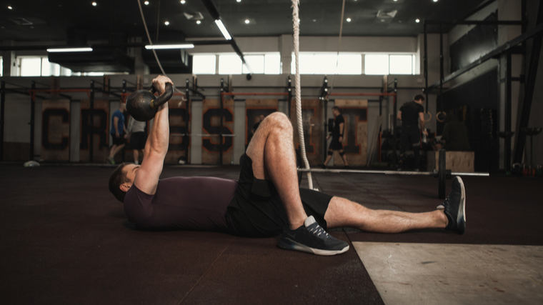 A person performs a Turkish get-up in the gym.