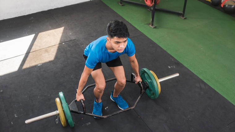 A person prepares to perform a trap bar deadlift.