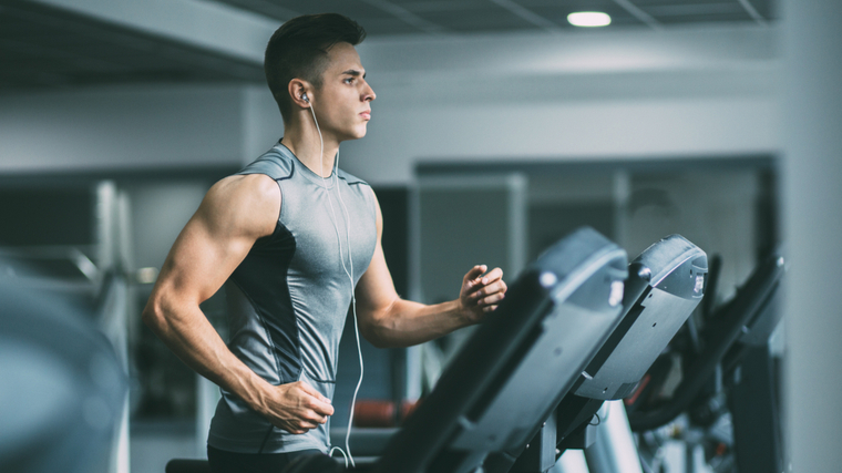 A person wears a grey tank top while running on a treadmill.