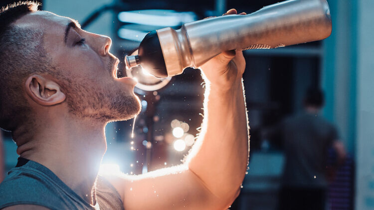 A person drinks from a water bottle while sweating.