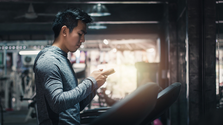 A person looks at their phone on a treadmill.