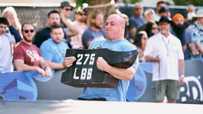 Strongman Mitchell Hooper carrying an anvil during the 2022 World's Strongest Man loading medley