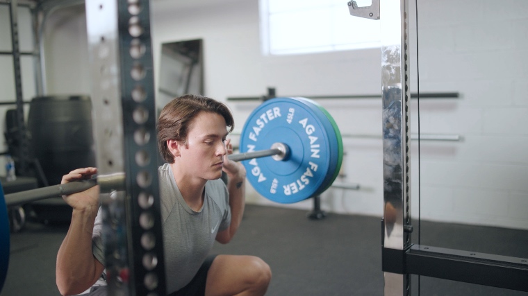 Jake squatting with the Again Faster Evo Bumper Plates
