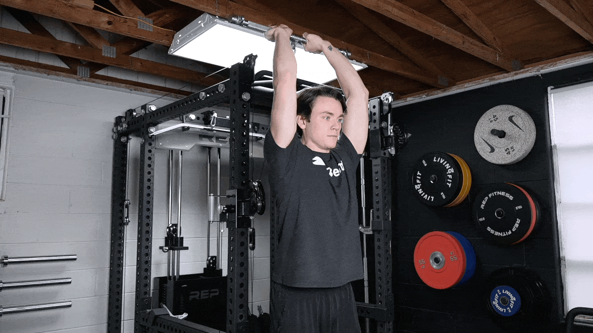 A person performing the cable overhead triceps extension.