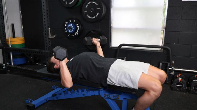 A person performing the dumbbell bench press exercise.