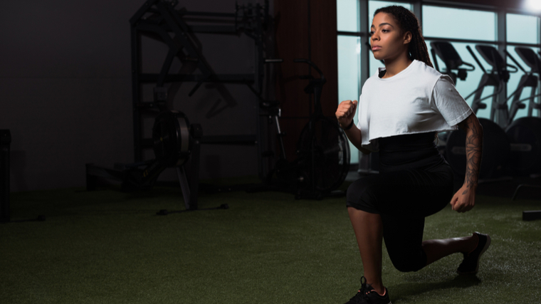 A person wears a white shirt and performs walking lunges.