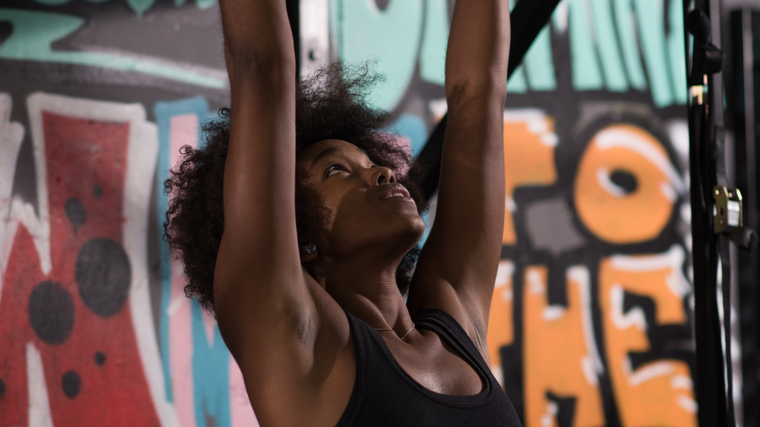 A person wears a sports bra while preparing to perform a pull-up outside.