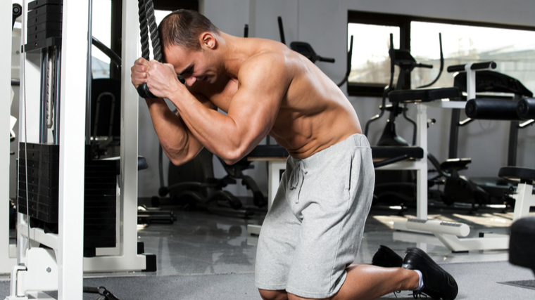 A shirtless person starts performing a cable crunch.