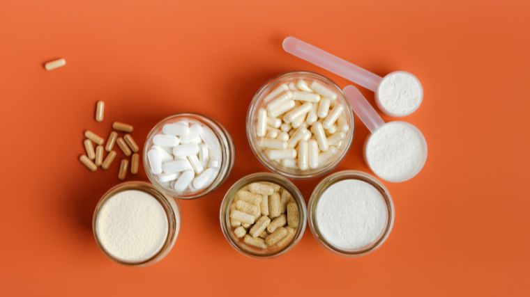 jars of supplement capsules and powders on a plain orange background