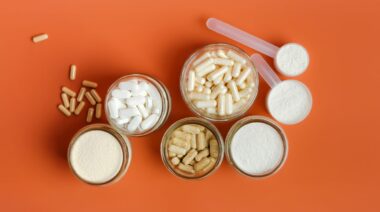 jars of supplement capsules and powders on a plain orange background