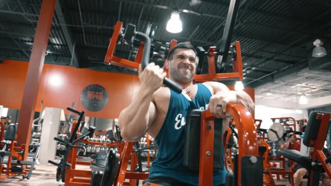 person in blue tank top performing a machine lat pulldown