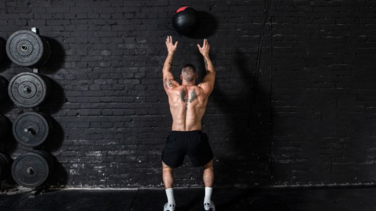 man performs medicine ball thruster