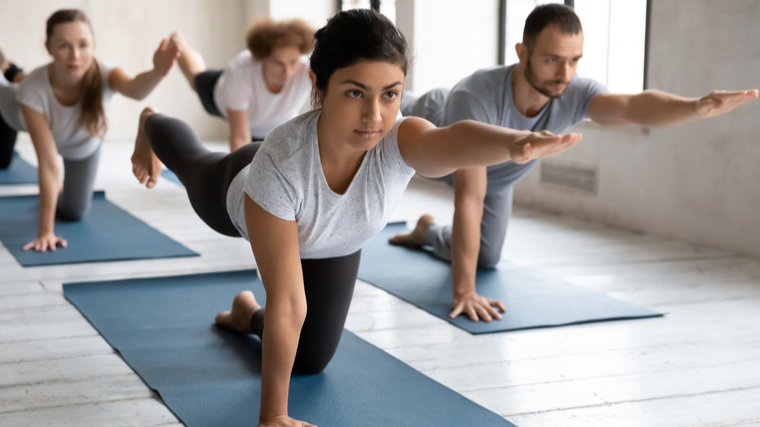 Several people focus while performing bird dogs in a group fitness class.