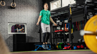 A person wearing a bright green shirt performs double unders in a functional fitness gym area.