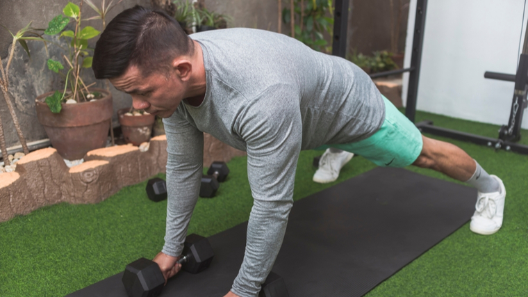 A person wears a long-sleeved gray shirt while preparing to perform a renegade row.