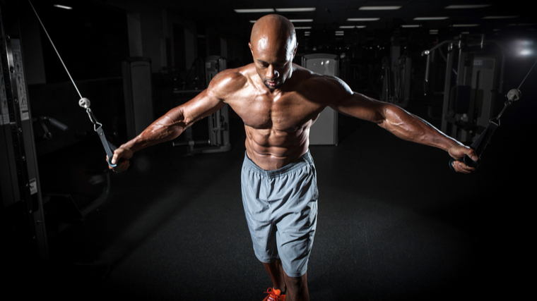 A shirtless person performs a cable chest flye.