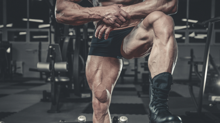 A person wears short shorts and stands with one leg on a bench in the gym.