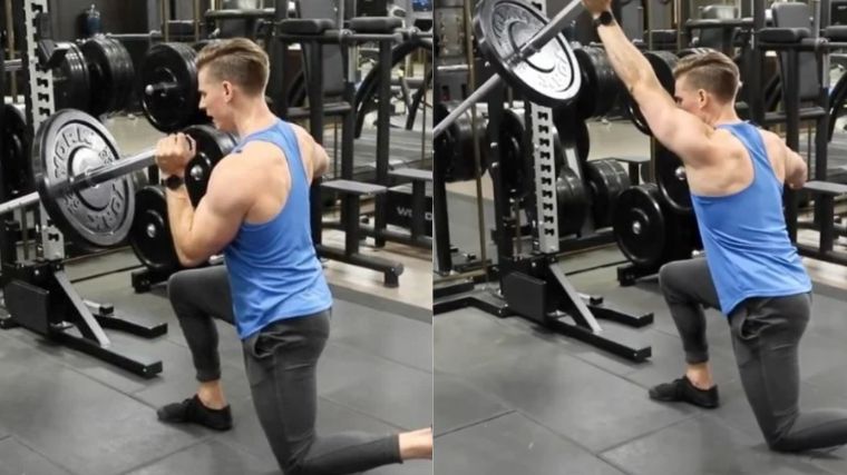 Person in blue tank top and black pants performing a half-kneeling landmine press.