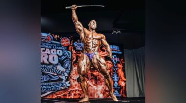 Bodybuilder Antoine Valliant hoists a sword above his head at the 2022 Chicago Pro