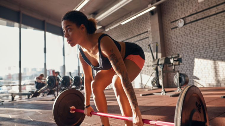 A person prepares to perform a deadlift in a gym.