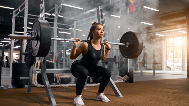 Women perform squats on racks 