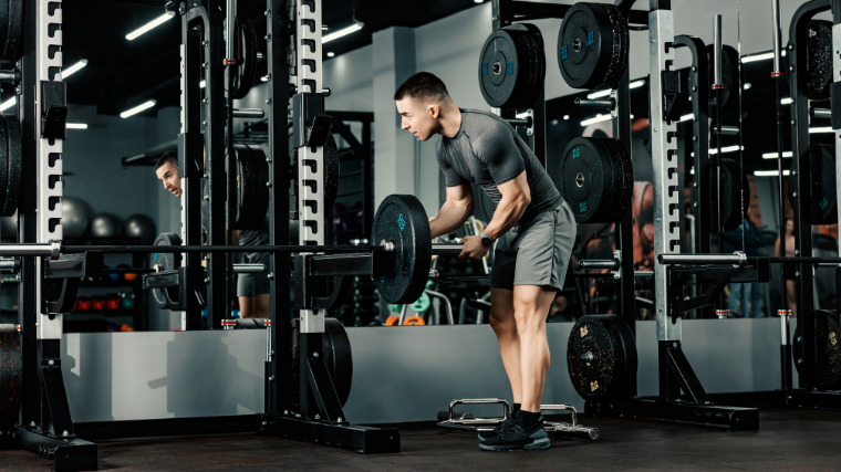 man loads barbell in power rack