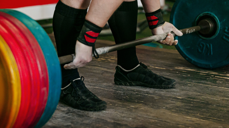 powerlifter prepares to pull weight in deadlift slippers