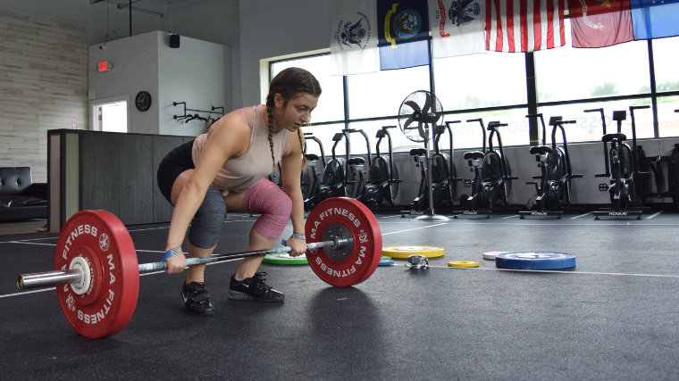 Weightlifter sets up for clean exercise in gym 