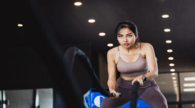 A person performs battle rope waves in the gym.