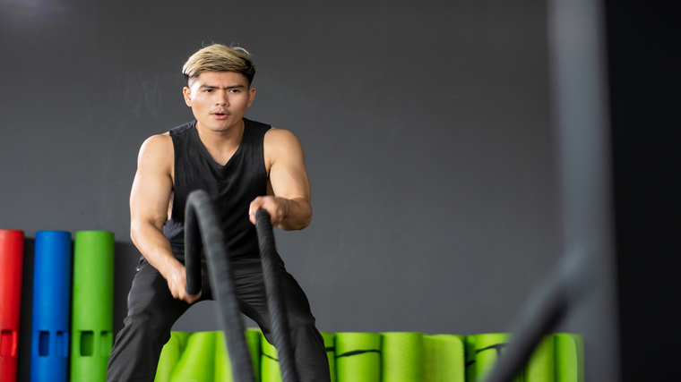 A person performs battle rope waves in the gym.