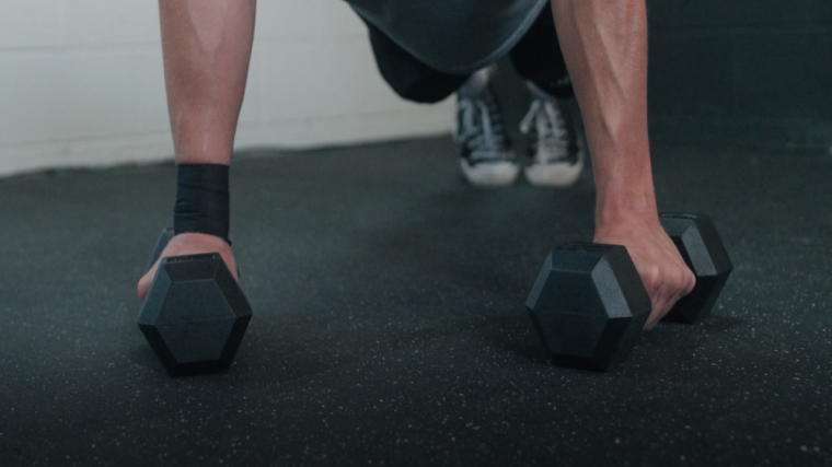 A BarBend tester using the Living.Fit Dumbbells for pushups.