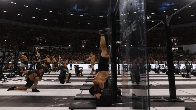 Games athletes perform deficit wall-facing handstand push-up in Event Seven of the 2022 CrossFit Games.