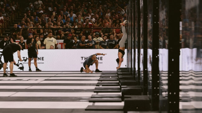 A Games athlete holds the top of a handstand push-up in Event Seven of the 2022 CrossFit Games.