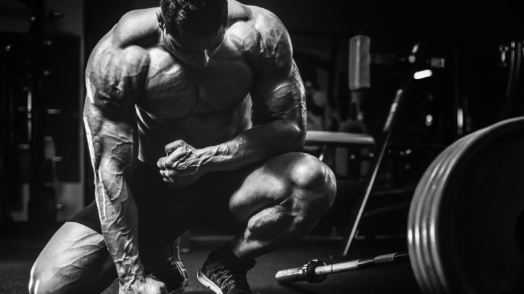 Bodybuilder kneeling with fist on ground